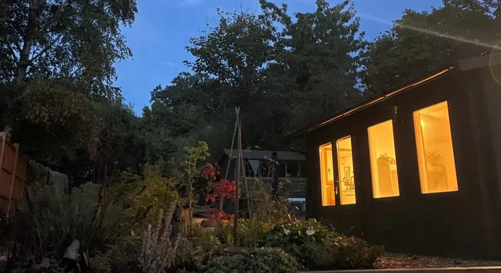 Sally Varley’s garden clinic cabin lit warmly at dusk